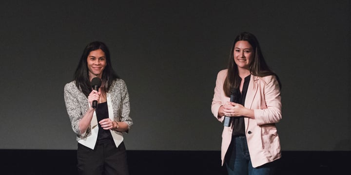 Jessamine Chin and Erin Baudo Felter on a stage holding microphones