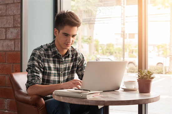 person typing on a laptop in a cafe