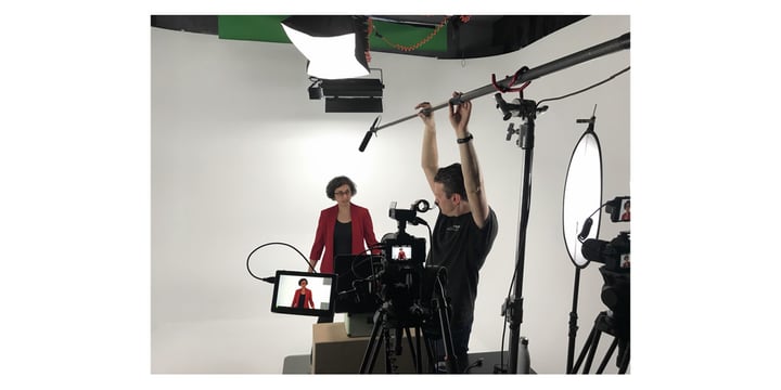 recording setup showing camera, microphone, lights, white backdrop, instructor, and technician