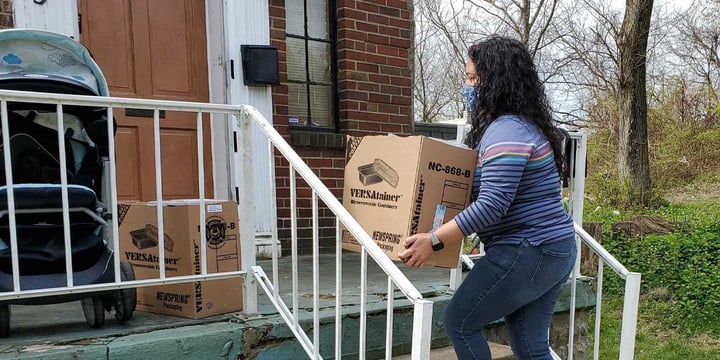 masked woman placing boxes of food on a front porch