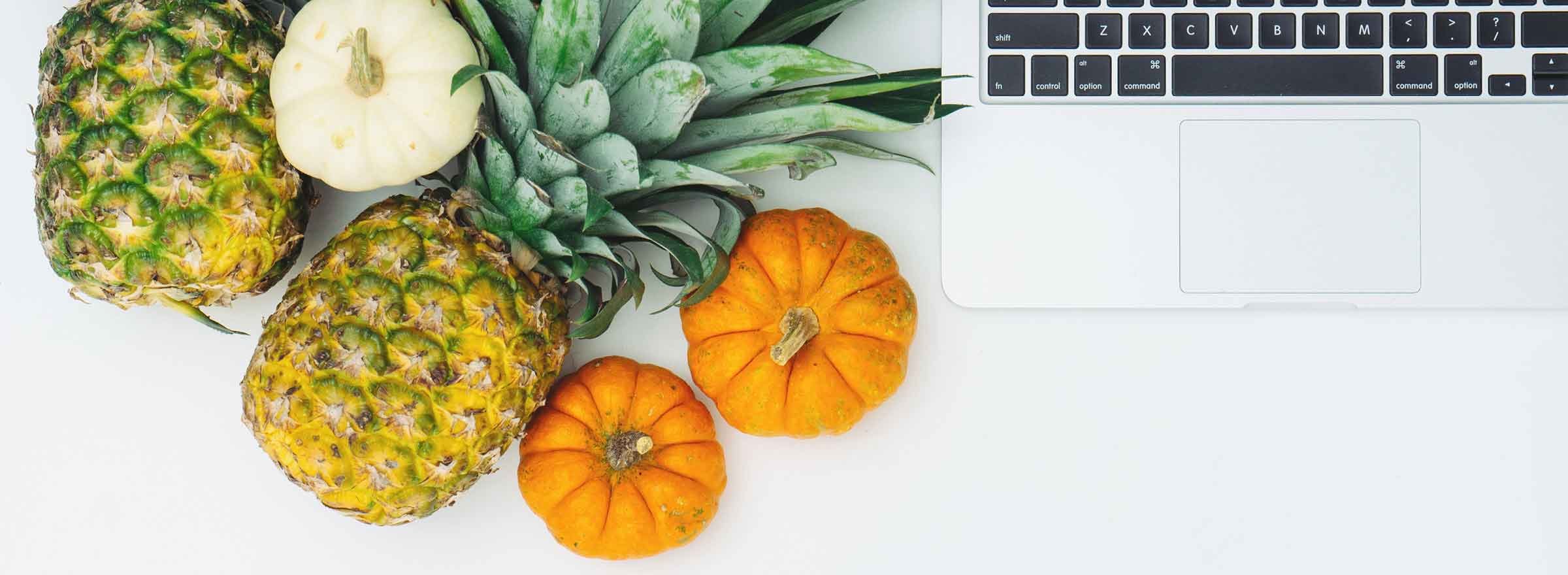 pineapples and pumpkins next to a laptop keyboard representing how Symantec helps nonprofits promote healthy eating
