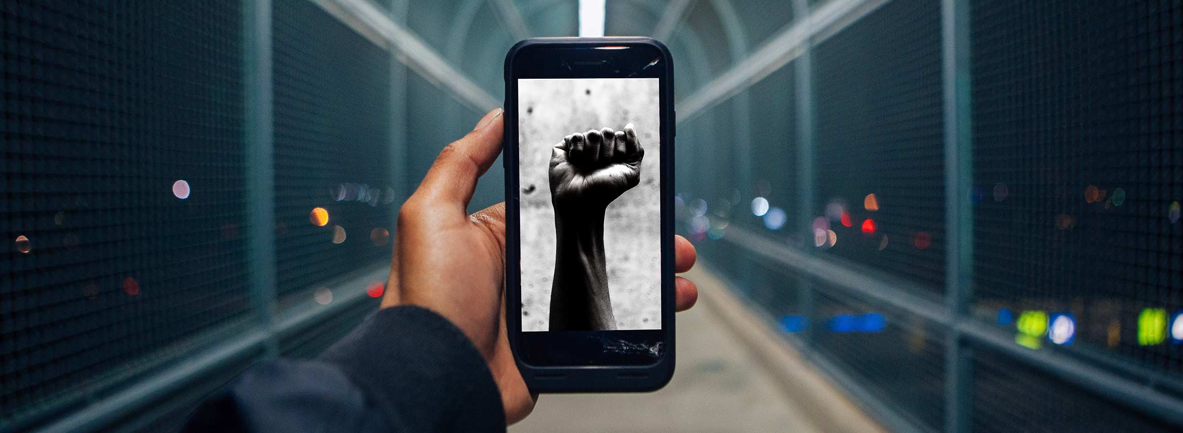 person looking at an image of a raised fist on a phone, symbolizing how public good app house is empowering positive social change