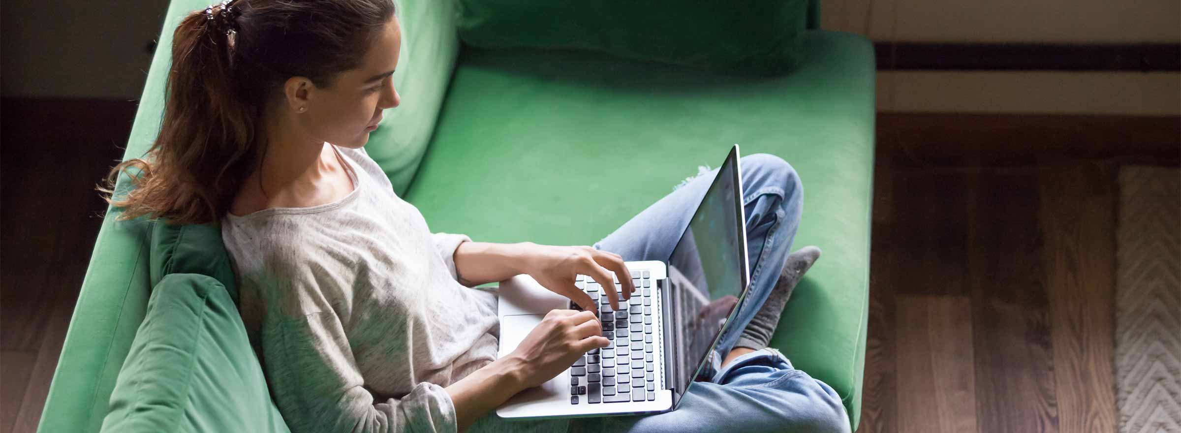 woman sitting cross-legged on a sofa and using a laptop