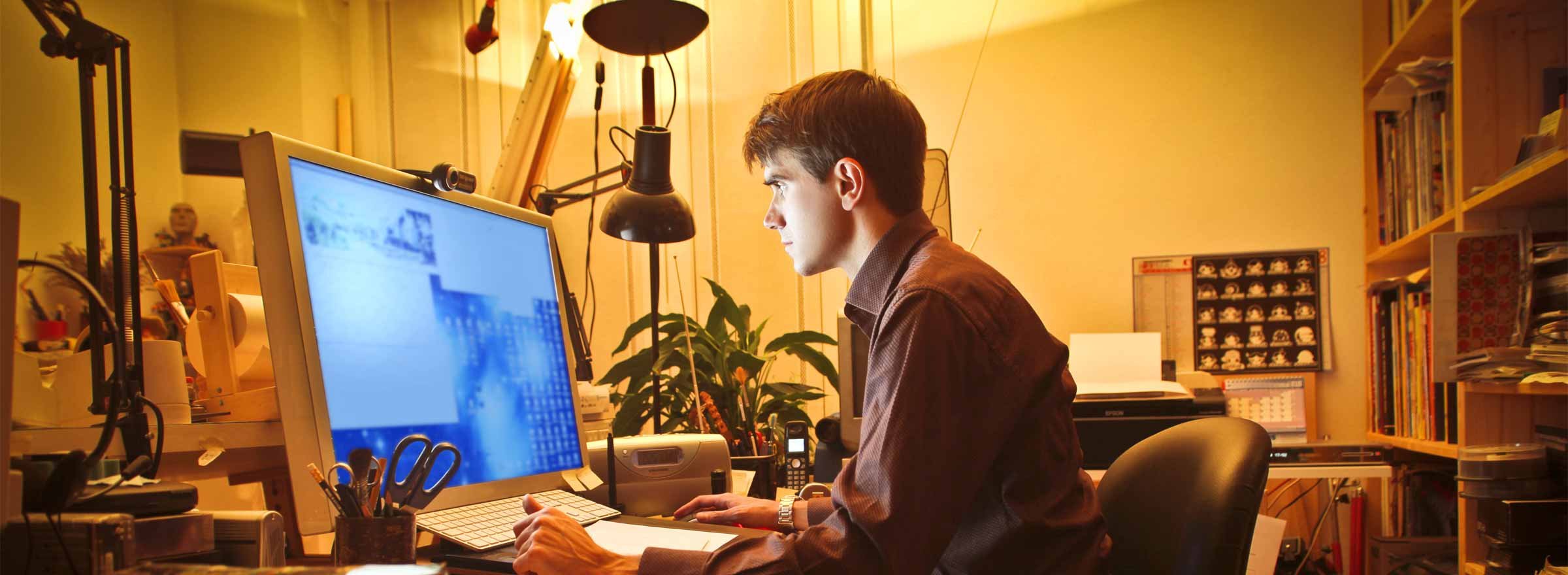 man working at home on a large computer screen