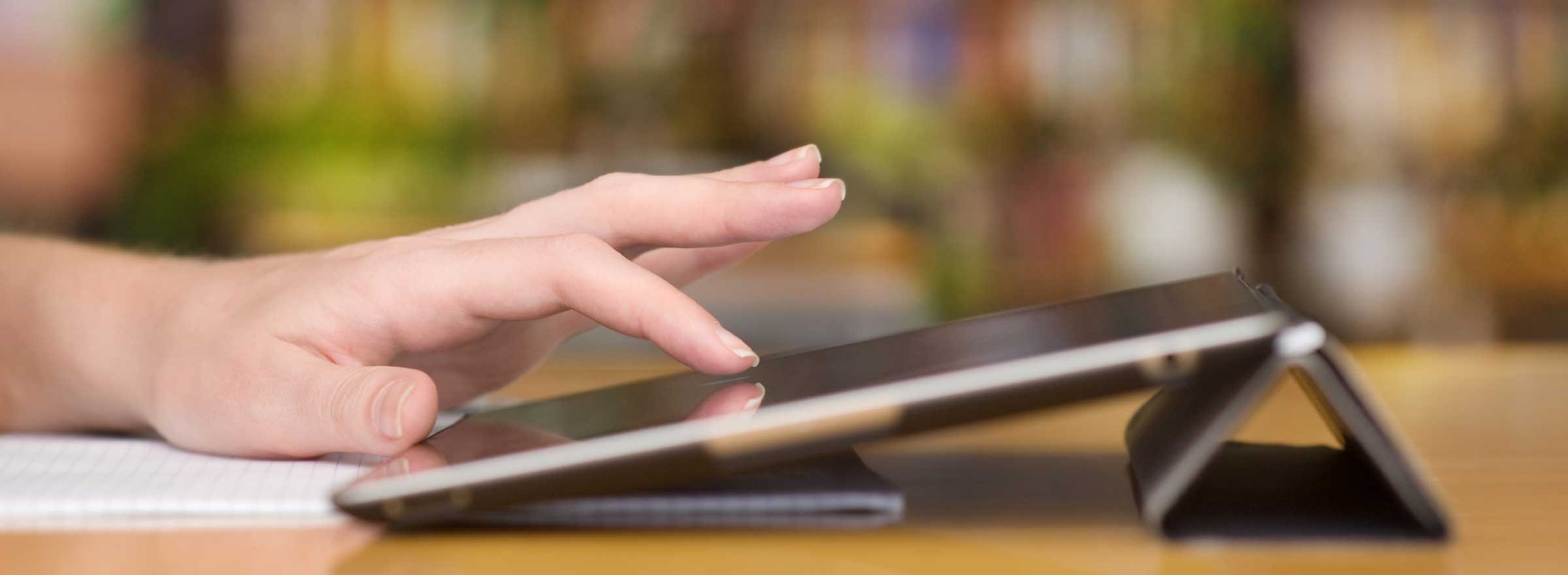 a hand on a tablet on a library table