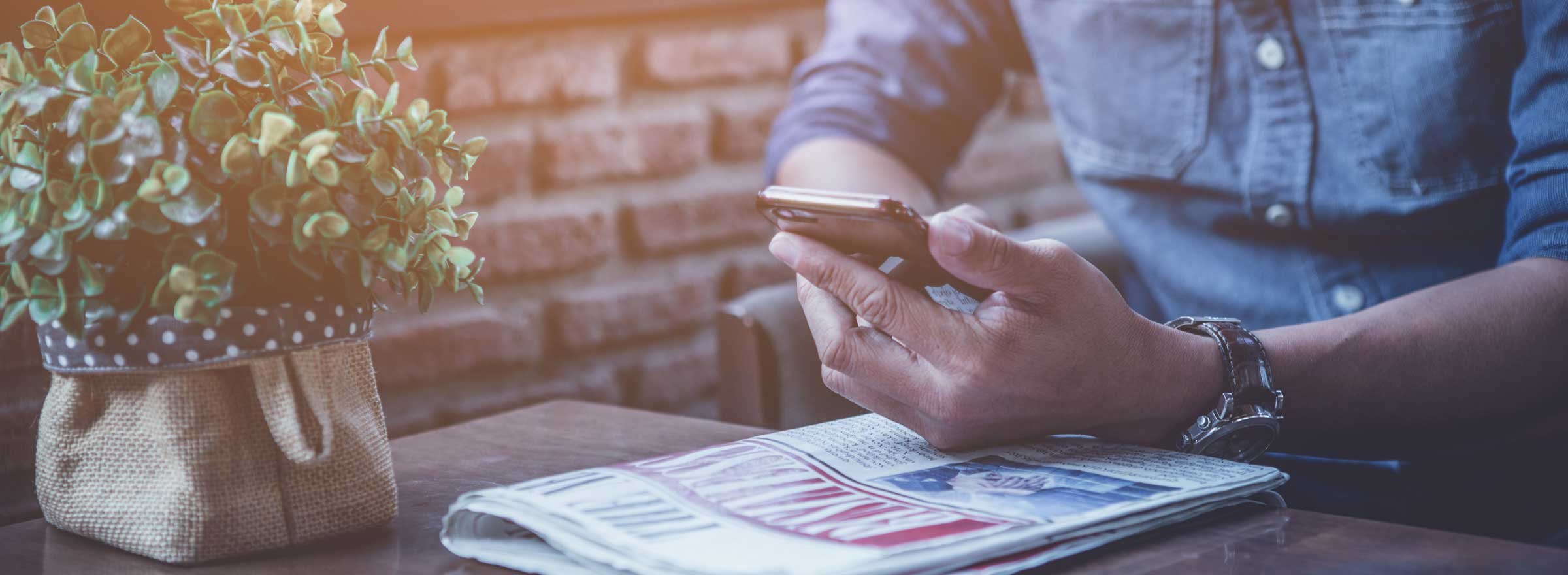 man sitting at a table with a newspaper and a smartphone