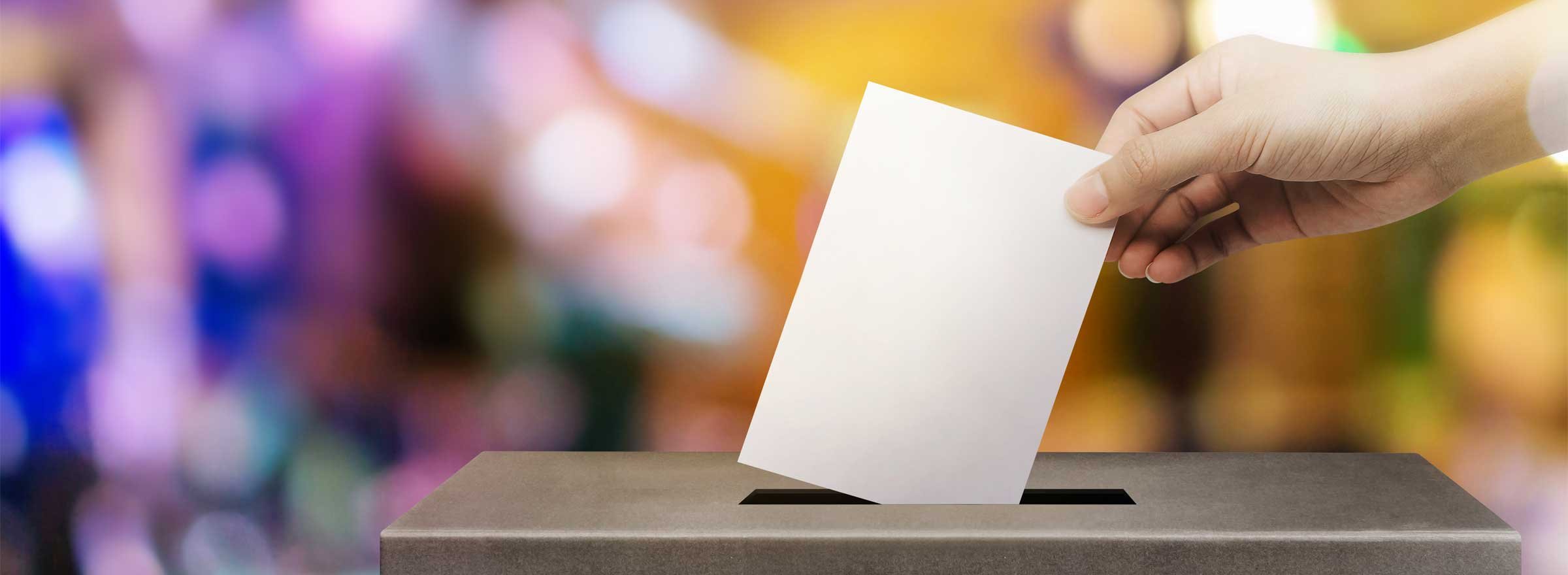 hand inserting a ballot into a box