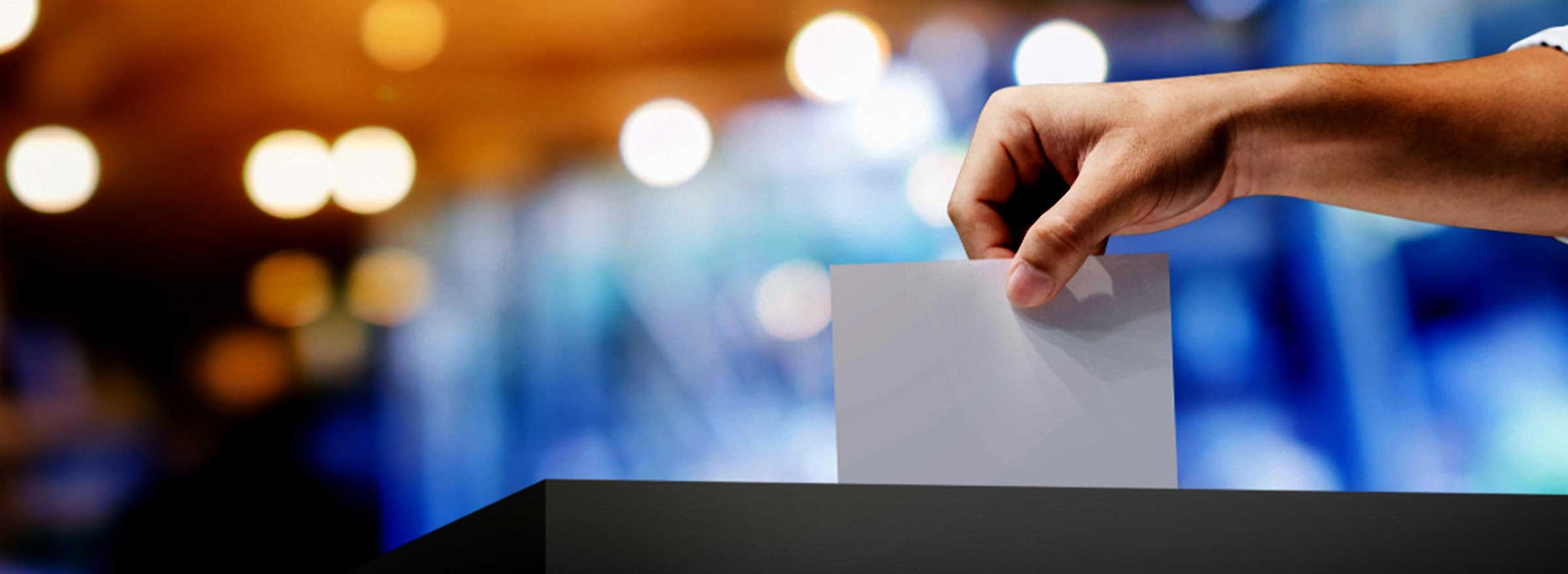hand placing a ballot in a box