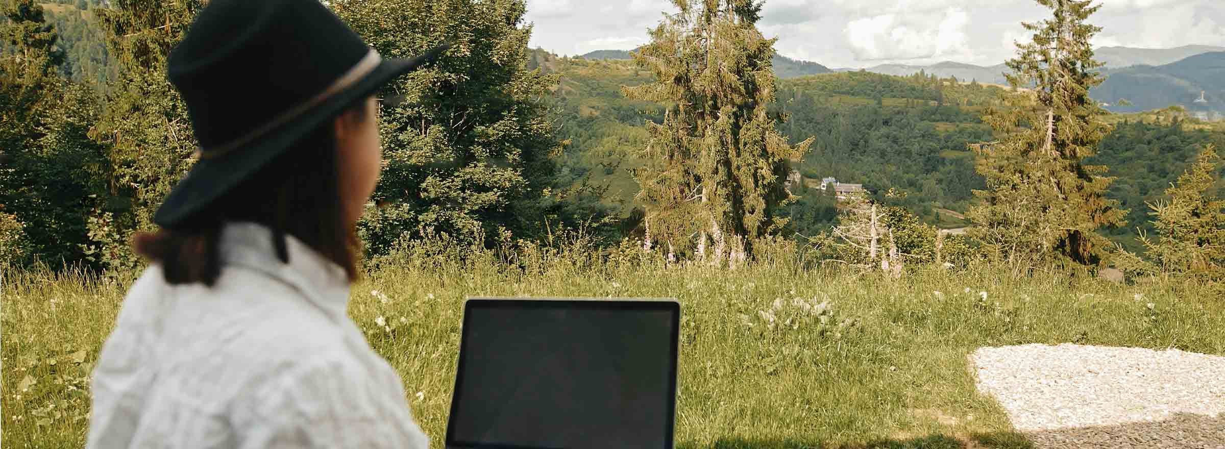 woman using a laptop outdoors in hilly country