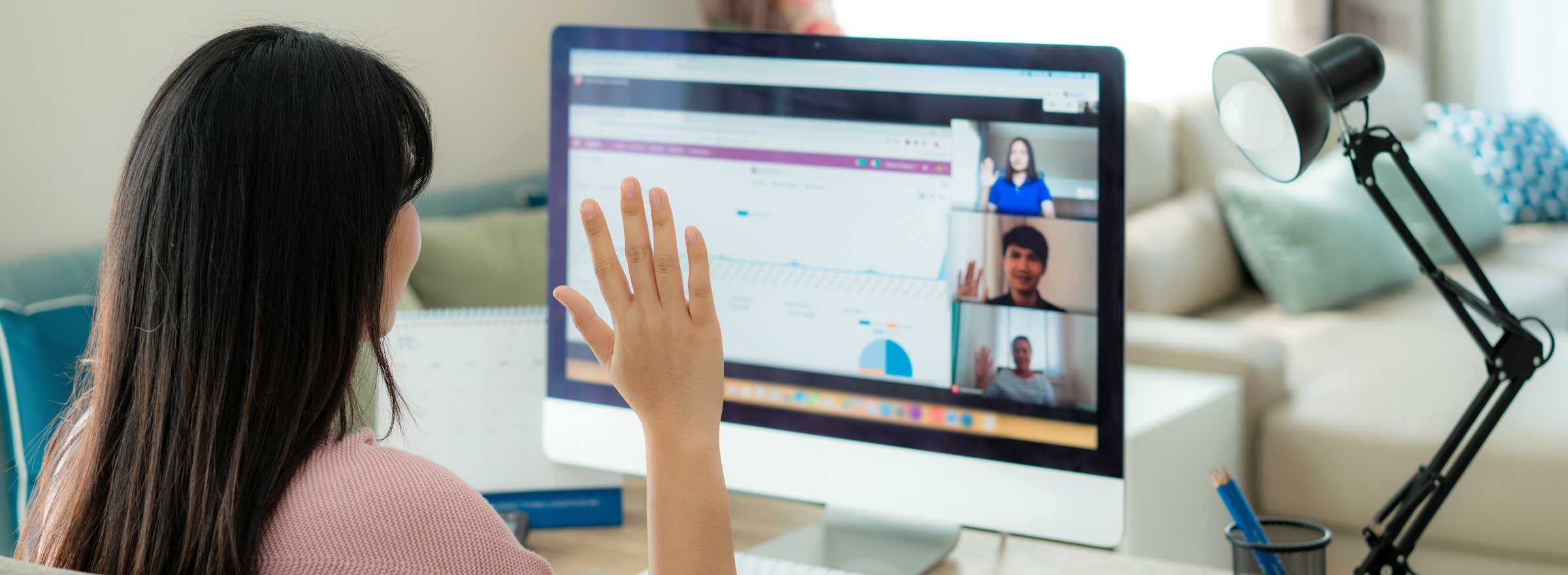 four people in a video conference raising their right hands