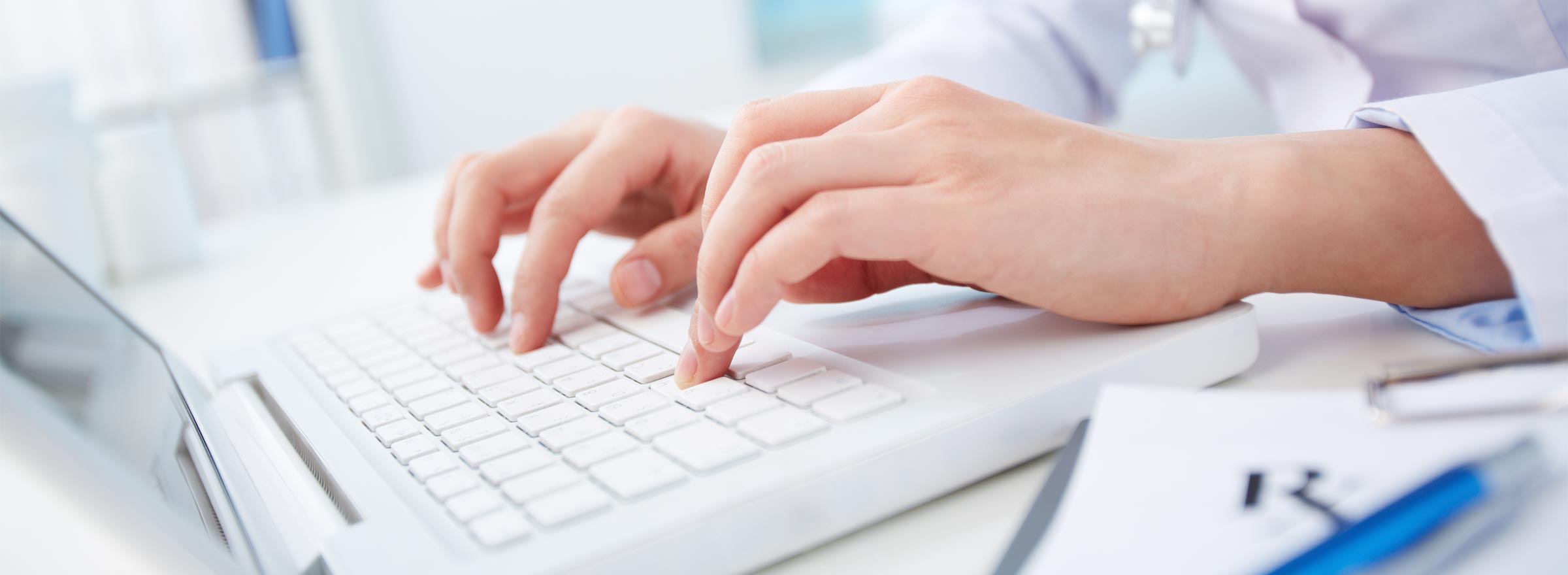 hands of a medical professional typing on a laptop