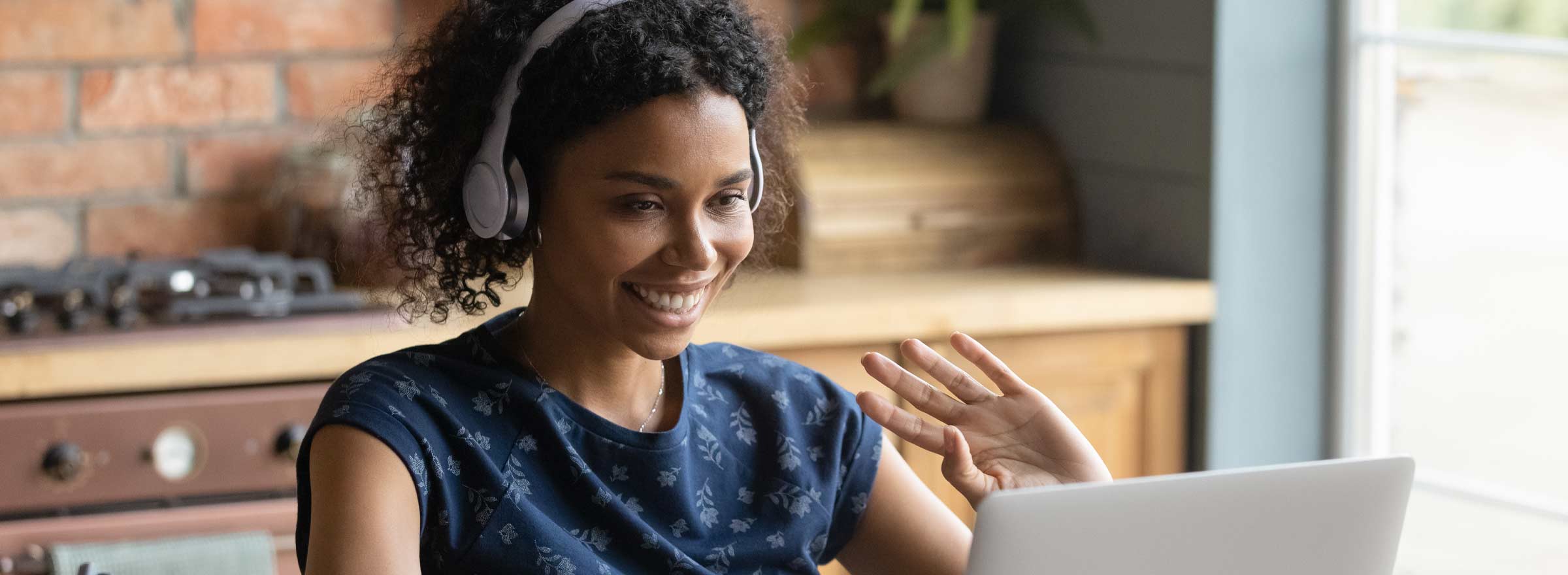 woman in headset waving at a computer screen