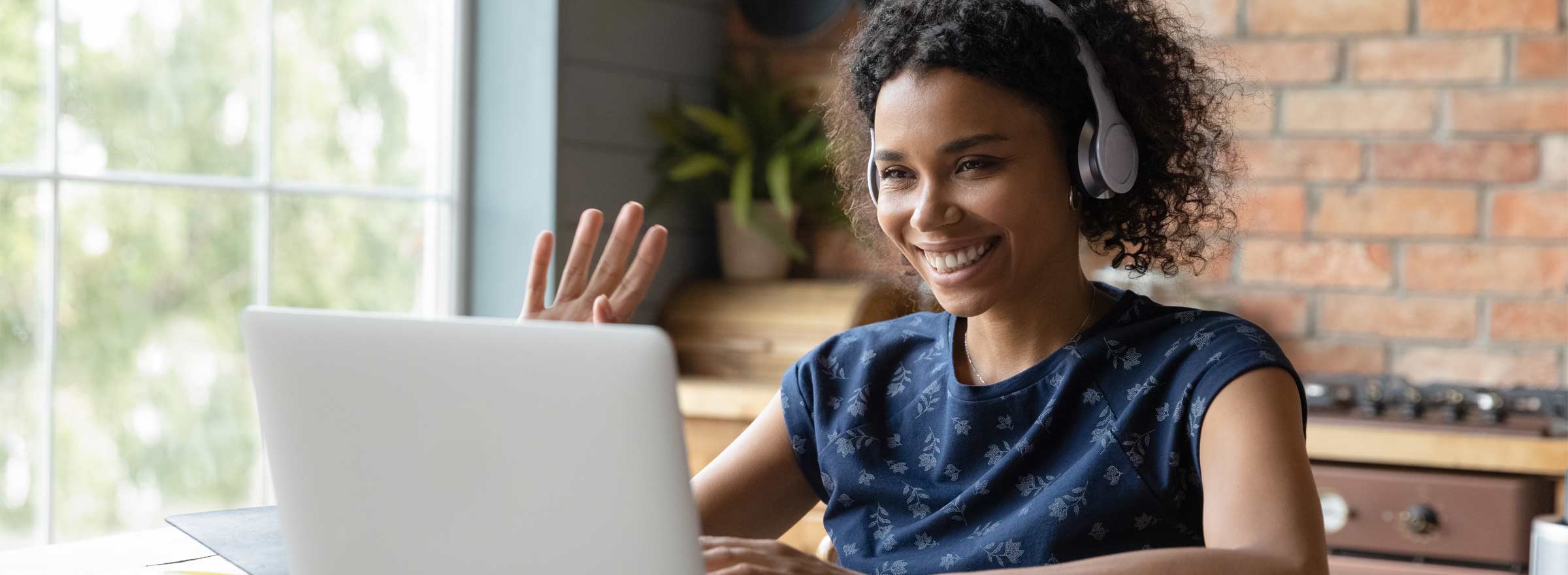 woman smiling and waving at computer screen