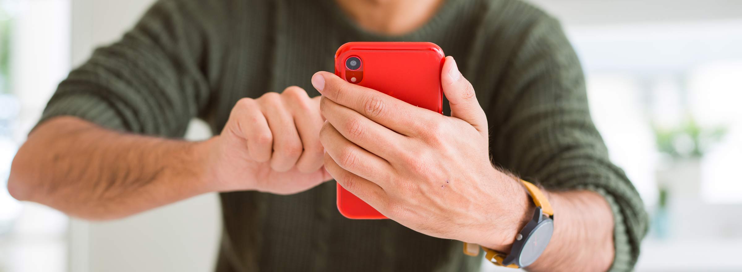 arms of a man using a red smartphone