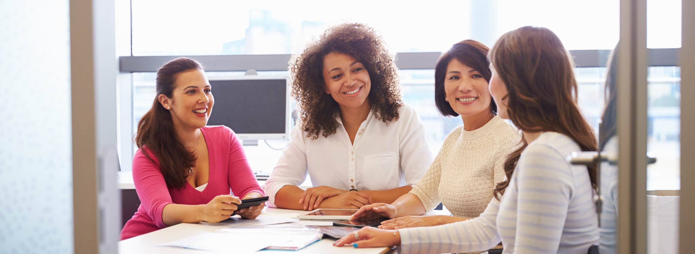 diverse group of four women meeting at a conference table