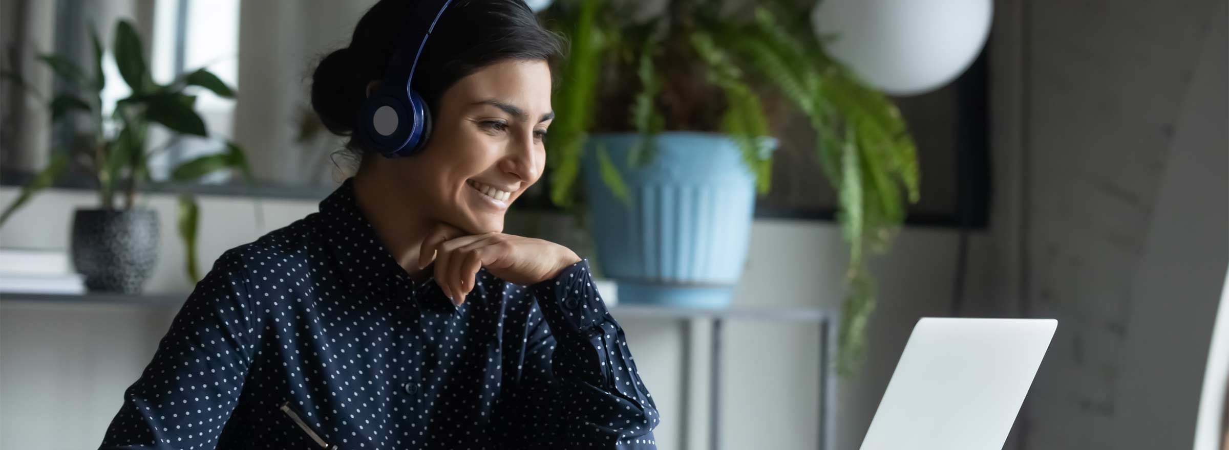 woman with headphones smiling at a computer screen